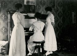 Three young women around piano