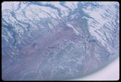 Red canyon in snow-covered Rocky Mtns. below Pan-Am jet. Los Angeles - London.