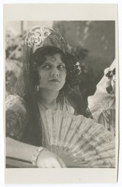 Item 0069. Another young woman in a dark mantilla, holding a fan. A second woman is partially visible at extreme right.