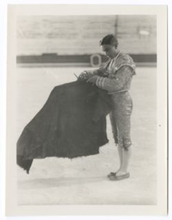 Item 0123a. Three similar shots of another matador posed with his working cape held perpendicularly in front of himself. Empty seats of arena in background. Full-length shot