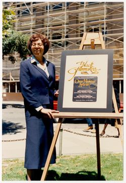 Mary Perry Smith beside 13th Annual Oscar Micheaux Awards Ceremony poster