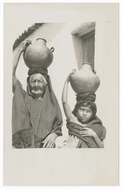 Item 03. Elderly women seen in photo Items 45-47 with small girl, both holding large jugs on their heads.