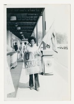 Man holding flag and wearing "on strike" sign