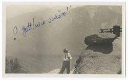 Item 38. Eisenstein, lower center, standing on hillside beneath rocky ledge with railing on top, mountains in background. See photo Items 535 and 1190 for similar location.