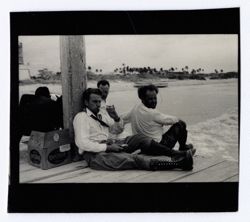 Item 1176. - 1179. On a dock, with breakers, beach and coast in background. Alexandrov, Kimbrough and Eisenstein, with unidentified others, seated on a dock eating and drinking. See also Item 512 above.