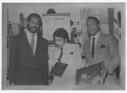 Morris Day, Danny Glover, and unidentified man holding BFHFI plaque and gold record