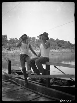 Billie and Bud on ferry rail, drinking