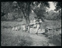Man and children sitting by creek