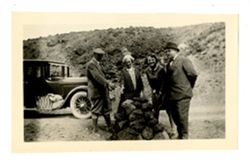 Group of men and women standing beside a rock pile