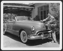 Hoagy Carmichael posing near his 1948 Oldsmobile at his California home.