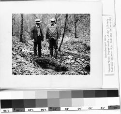 Two unidentified men standing at grave on Scott Richards' farm