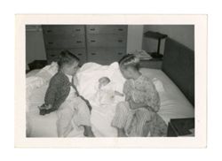 Two young children and a baby on a bed
