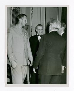 Roy Howard greeting other men at an event