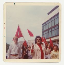 Woman in red shirt leading group waving flags