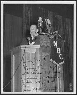 Hoagy Carmichael standing at a podium with a NBC microphone and banner.