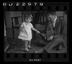 Item 1171a. Medium shot of Alexandrov, seated on floor holding a camera (?) and same child, looking toward photographer.