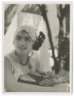 Item 0066. Young woman in mantilla; cluster of flowers at left side of her head. Right arm raised as though it is resting on something; she holds an open fan in her hand. Also seen in Item 65 above, at left.