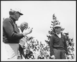 Unidentified man applauding Hoagy Carmichael on a golf green with spectators in background.