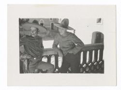 Item 0901. Two men wearing sombreros leaning on a railing.