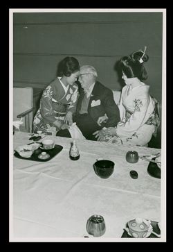 Roy W. Howard sitting between two women