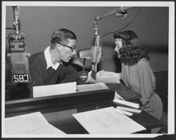 Hoagy Carmichael reading script into a CBS microphone with an unidentified woman.