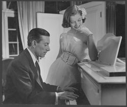 Hoagy Carmichael playing piano, with an unidentified woman standing beside him.