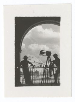 Item 1100. - 1100a. Long shots of Cathedral and plaza, taken through archway with railing in front. Men and camera on tripod silhouetted in opening. See also Item 879 above. Two men with camera. Maybe Tissé and Eisenstein.