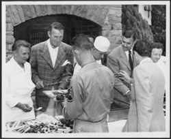 Group of people serving and receiving food, including Randolph Scott (2nd from left) and Clark Gable (3rd from right).