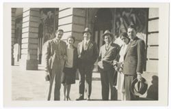 Item 37. Tissé (third from left), Eisenstein (third from right), and four other unidentified people (2 men, 2 women) standing in front of large building with murals around doorways.