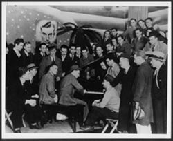 Hoagy Carmichael, at the piano, surrounded by friends at the Book Nook, Bloomington, Indiana.