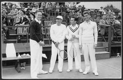 Hoagy Carmichael with three unidentified men on a tennis court with spectators in the background.