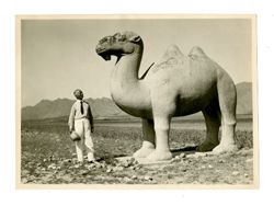 Man poses with camel statue