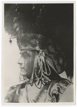 Profile of Indigenous person in bead and feather headdress and satin (?) blouse.