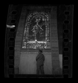 Item 0575. Eisenstein standing in front of large stained glass window.