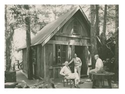 Three men posing for a photograph outside of cabin