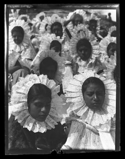 Large group of Indigenous women in "sunflower" headdresses.