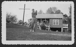 Hoagy Carmichael swinging golf club with unidentified people looking on.