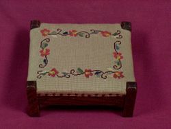 Foot stool with cross-stitch cover.