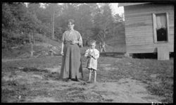 Lady with child in yard (near to Mrs. Foster and dogs)