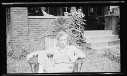 Martha Carmichael sitting in a wicker chair in the front yard.