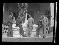 Item 0270. Five unidentified men in business suits on a patio with arches and house behind them. Grouped around a bench.