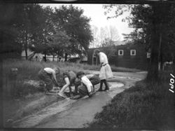 Boys and girls building mud dam near Studio