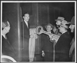 Unidentified men presenting Hoagy Carmichael with the key to the City of Indianapolis as he steps off of a train.