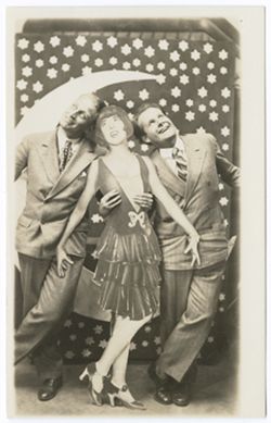 Item 53. Alexandrov and Eisenstein, with life-size cardboard cut-out of young woman between them, in front of backdrop with crescent moon and stars.