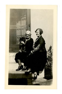 Two women and a dog sitting on a stoop