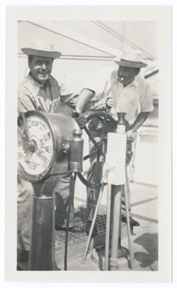 Item 0551. Kimbrough and two unidentified men standing by the wheel and engine room telegraph on the deck of a ship. Kimbrough, right, at wheel, and man in work clothes and straw (?) hat.