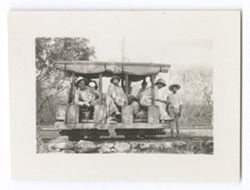 Item 1212. - 1212a. Crew members on a railroad cart with rolled-up awnings on the sides. Eisenstein seated center, Tissé seated right. Alexandrov seated left.