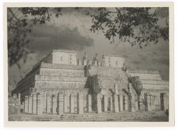 Item 0160. Close-up of Temple of the Warriors, framed by tree branch at left and top of photo. Front colonnade, main stairway and entrance to upper temple.