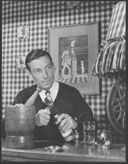 Publicity shot of Hoagy Carmichael at a wet-bar opening a bottle.