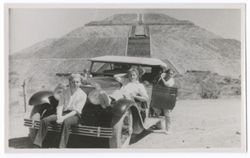 Item 39a. Alexandrov lying on left fender of ear, with same two unidentified men, one seated on front bumper and the other standing behind left rear passenger door. In background, the Temple of the Sun.